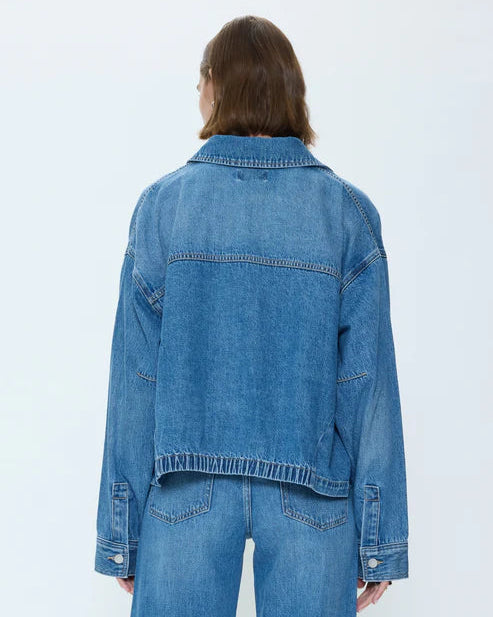 Person wearing a blue denim jacket and jeans on a white background