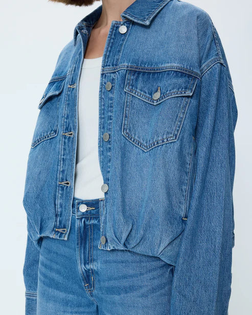 Person wearing a blue denim jacket and jeans on a white background