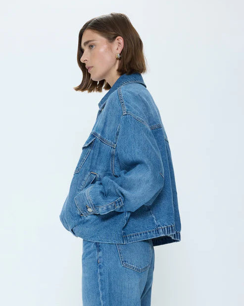 Person wearing a blue denim jacket and jeans on a white background