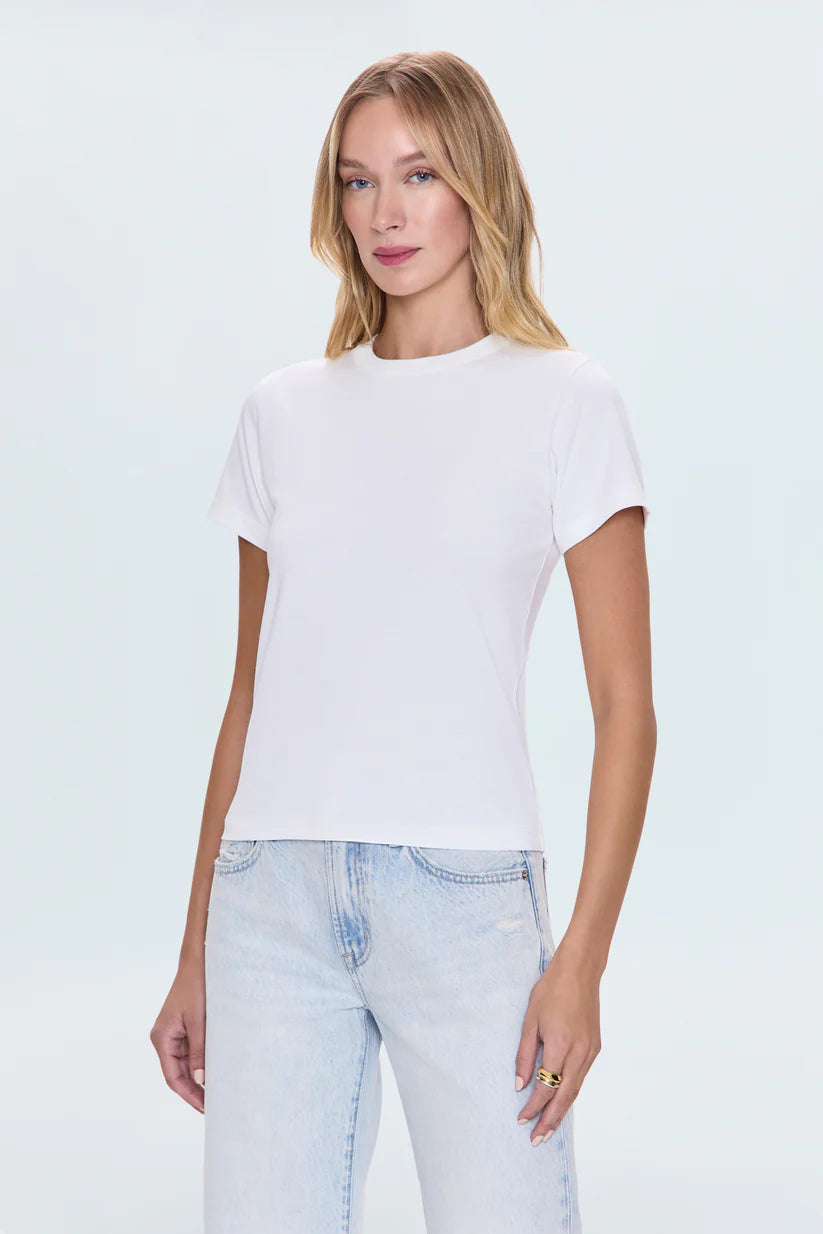 Woman wearing a white t-shirt and light blue jeans on a plain background