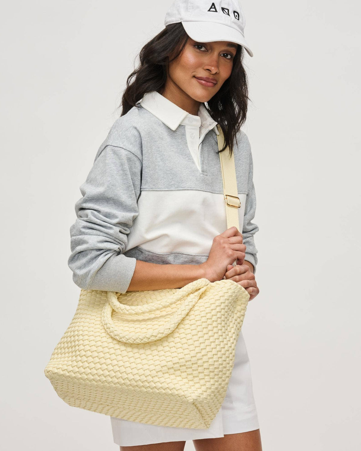 Woman holding a yellow textured bag against a plain background