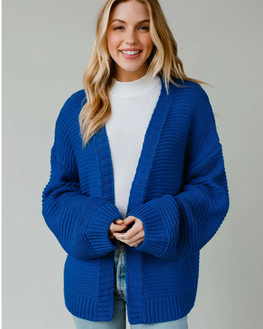 Model wearing Panache SKI Knit Cardigan in Blue/green on a beige background