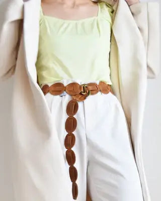 Person wearing a light green top, white pants, and a brown belt with a white coat.
