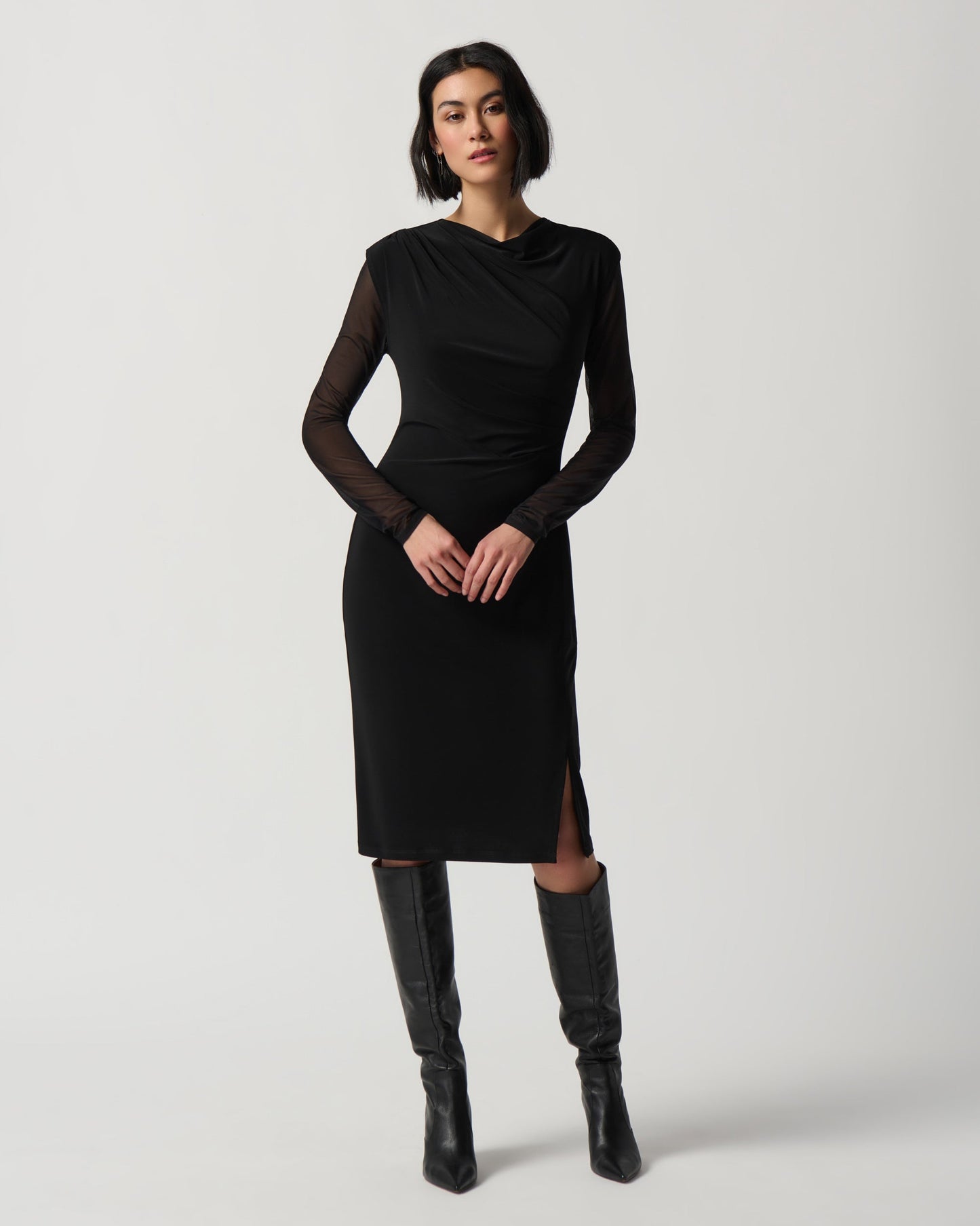 Woman wearing a black dress with sheer sleeves against a white background