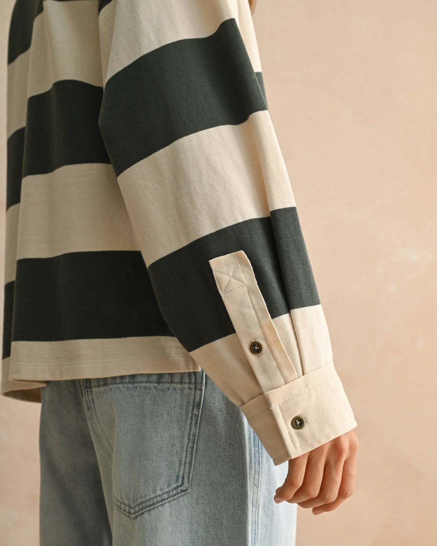 Green and beige striped shirt worn by a person on a beige background