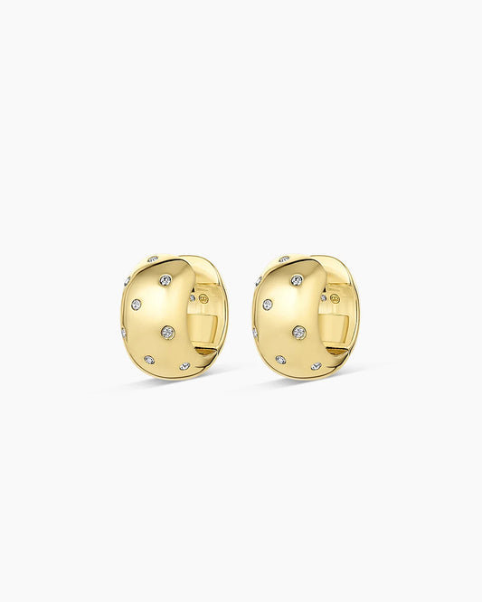 A pair of gold huggie hoop earrings with small clear pavé-set stones, shown on a clean white background.