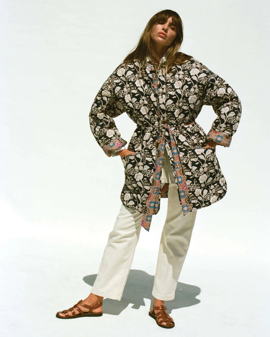 Person wearing a floral patterned coat with a plain background
