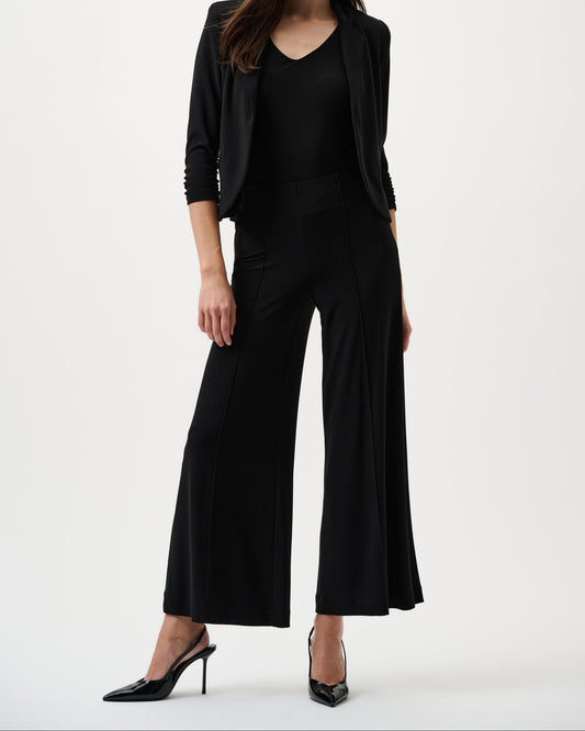 Woman wearing a black outfit with wide-leg pants on a white background