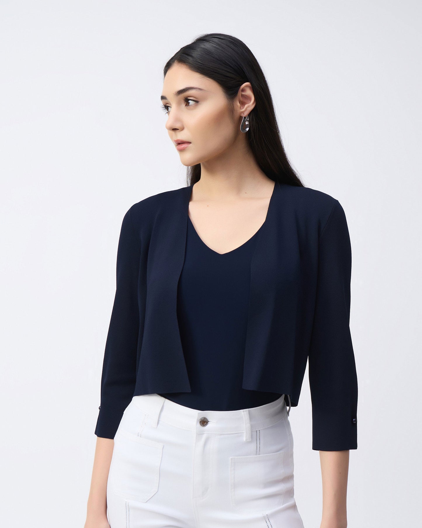 Model in a navy cover up with white pants in front of a white background