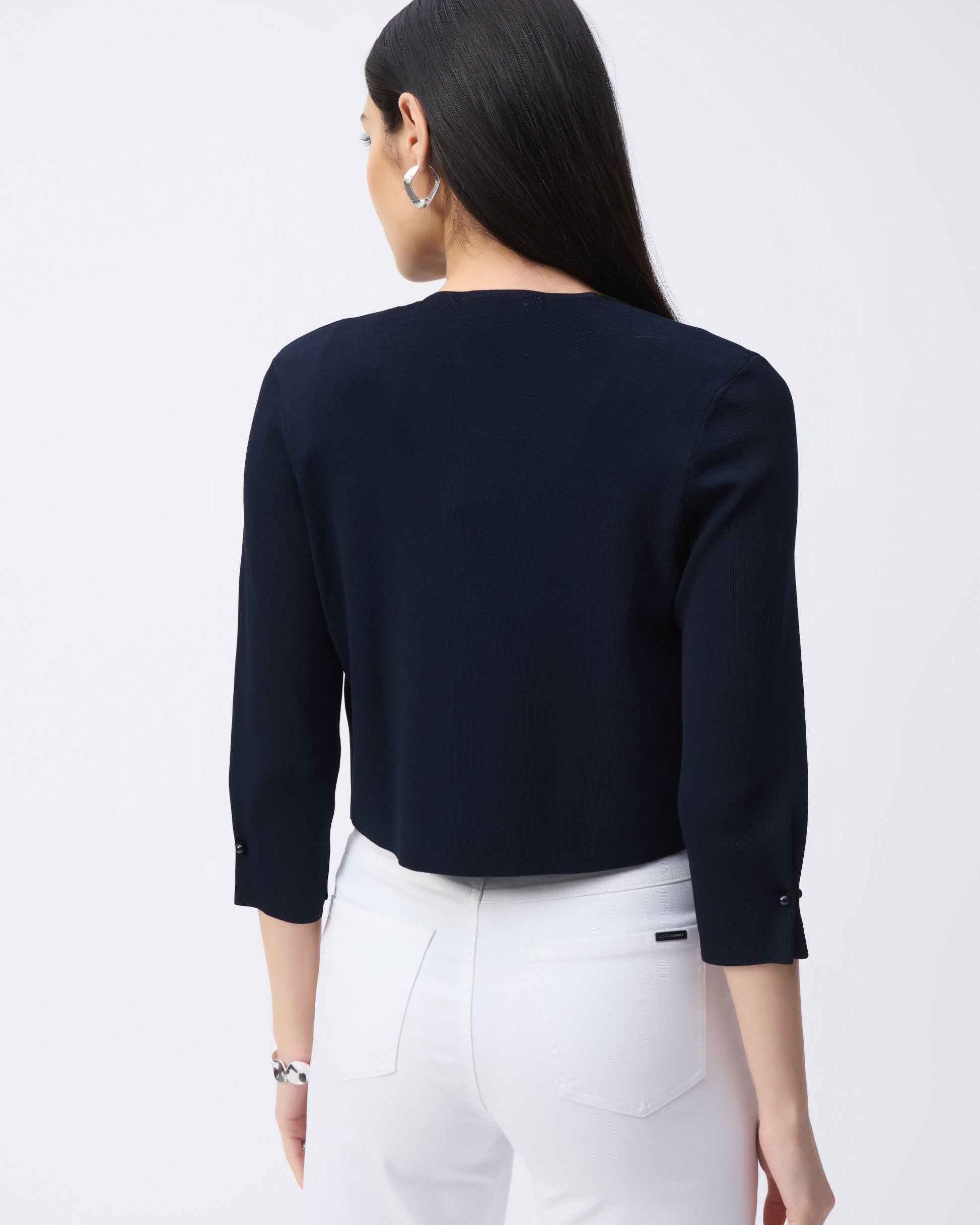 Back view of a navy coverup on a model  wearing white pants with a white background.