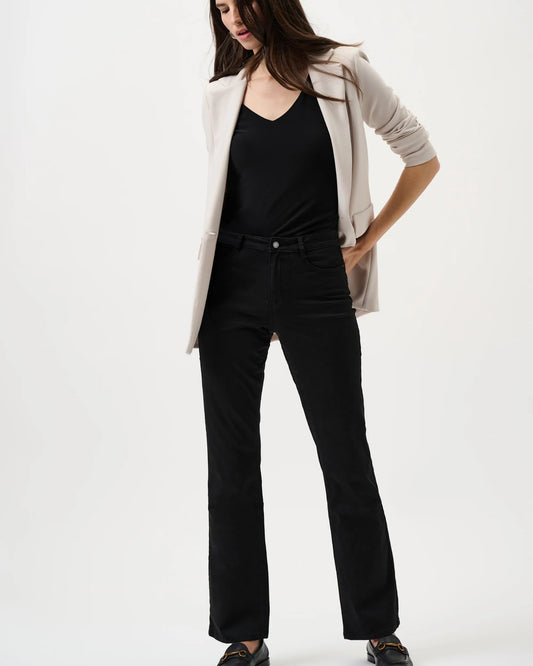 Woman wearing a beige blazer, black top, and black pants on a white background