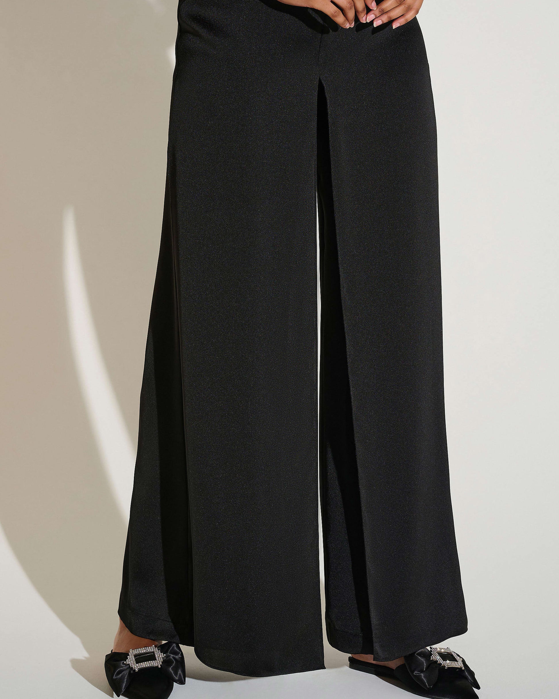 Person wearing black wide-leg pants on a plain background