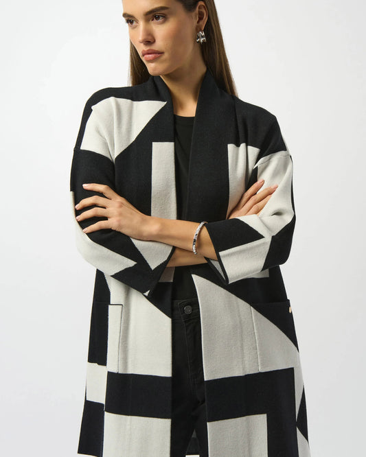 Woman wearing a black and white geometric patterned coat on a plain background