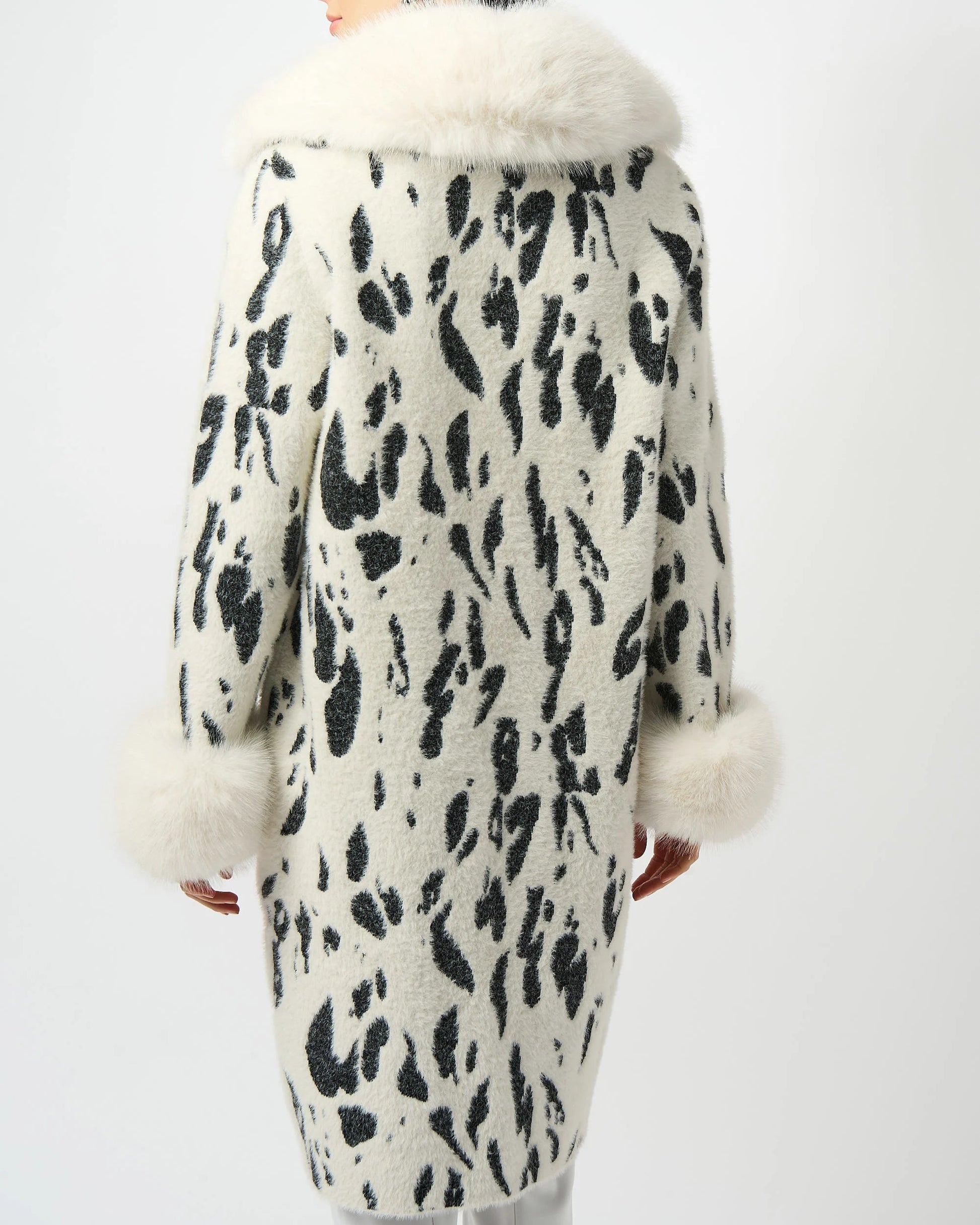 Woman wearing a leopard print coat with white fur trim on a white background