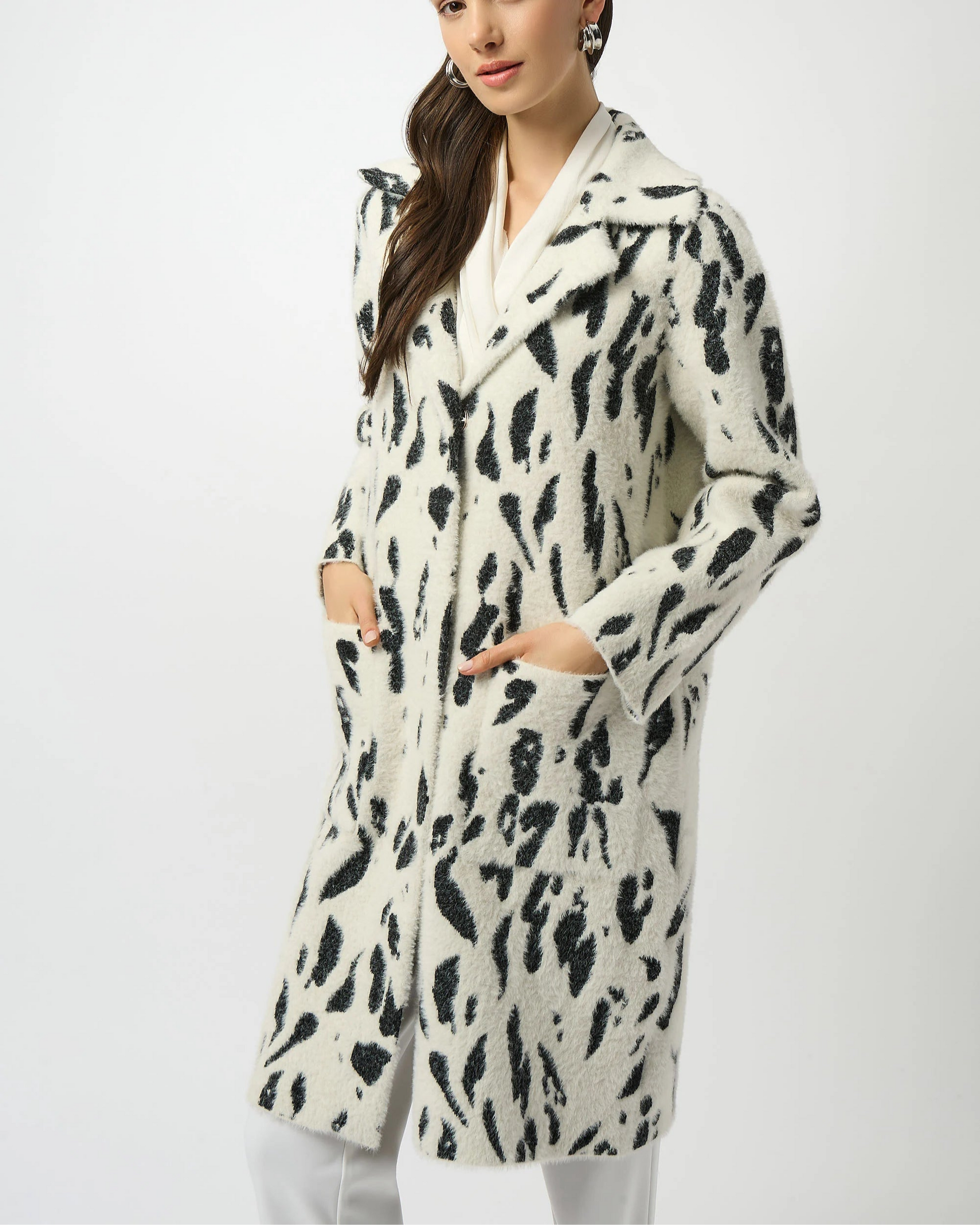 Woman wearing a long, patterned coat on a white background