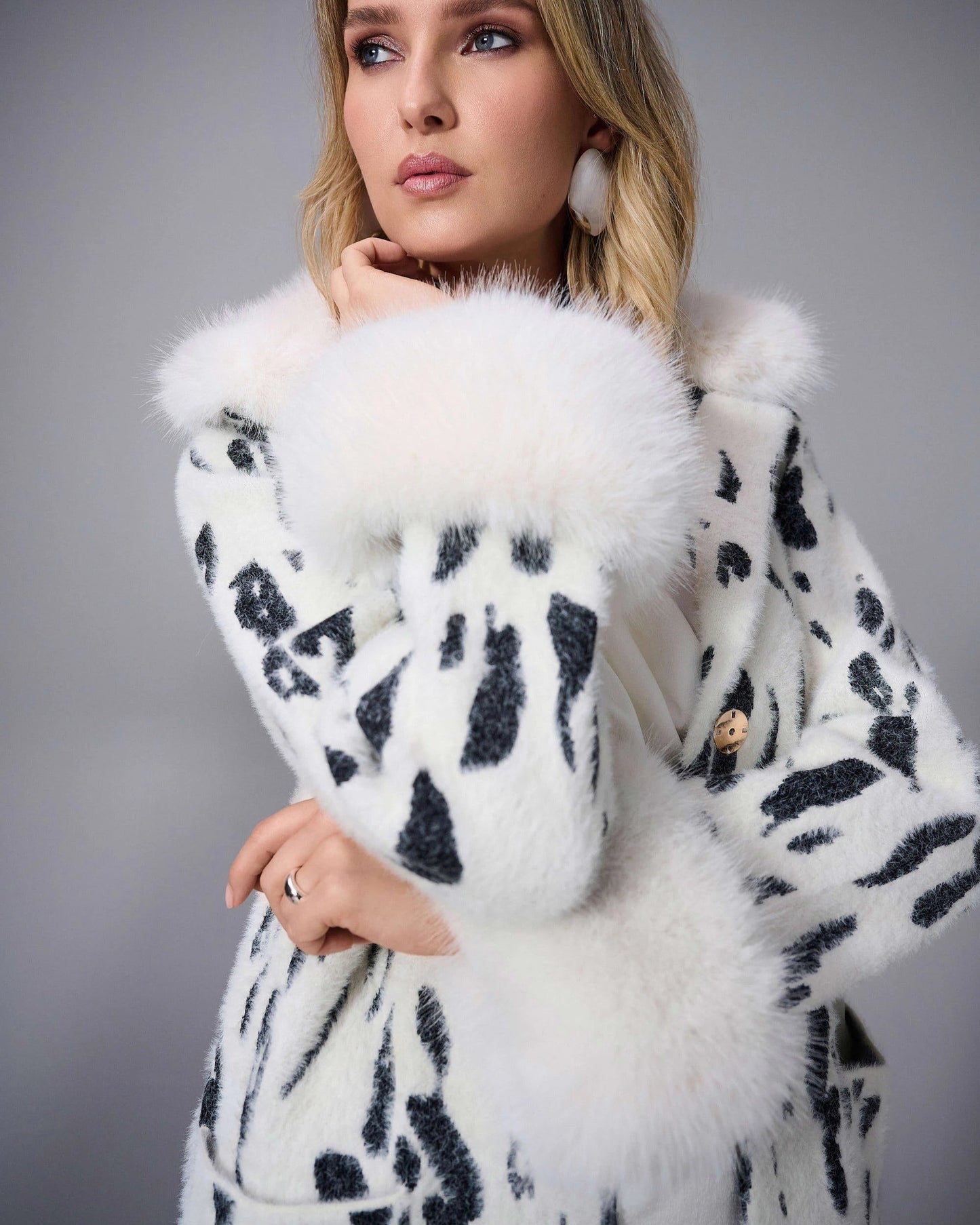 Woman wearing a white fur coat with black patterns on a gray background