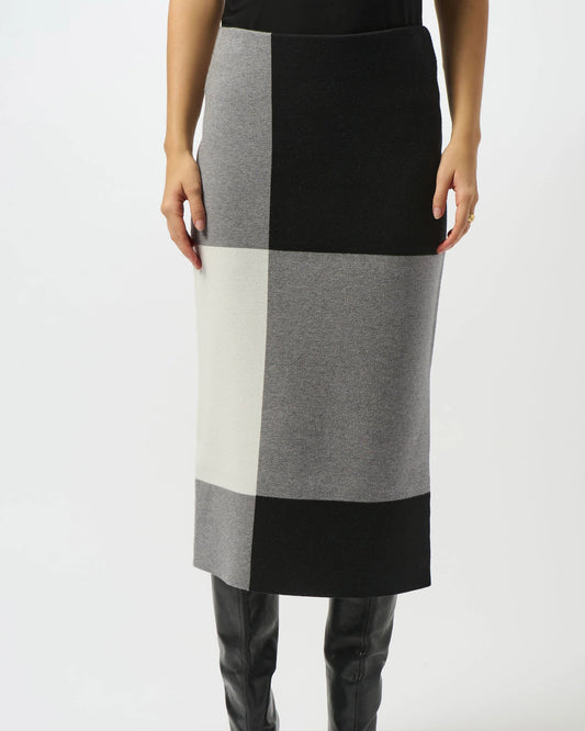 Person wearing a black, gray, and white checkered skirt with black knee-high boots on a white background