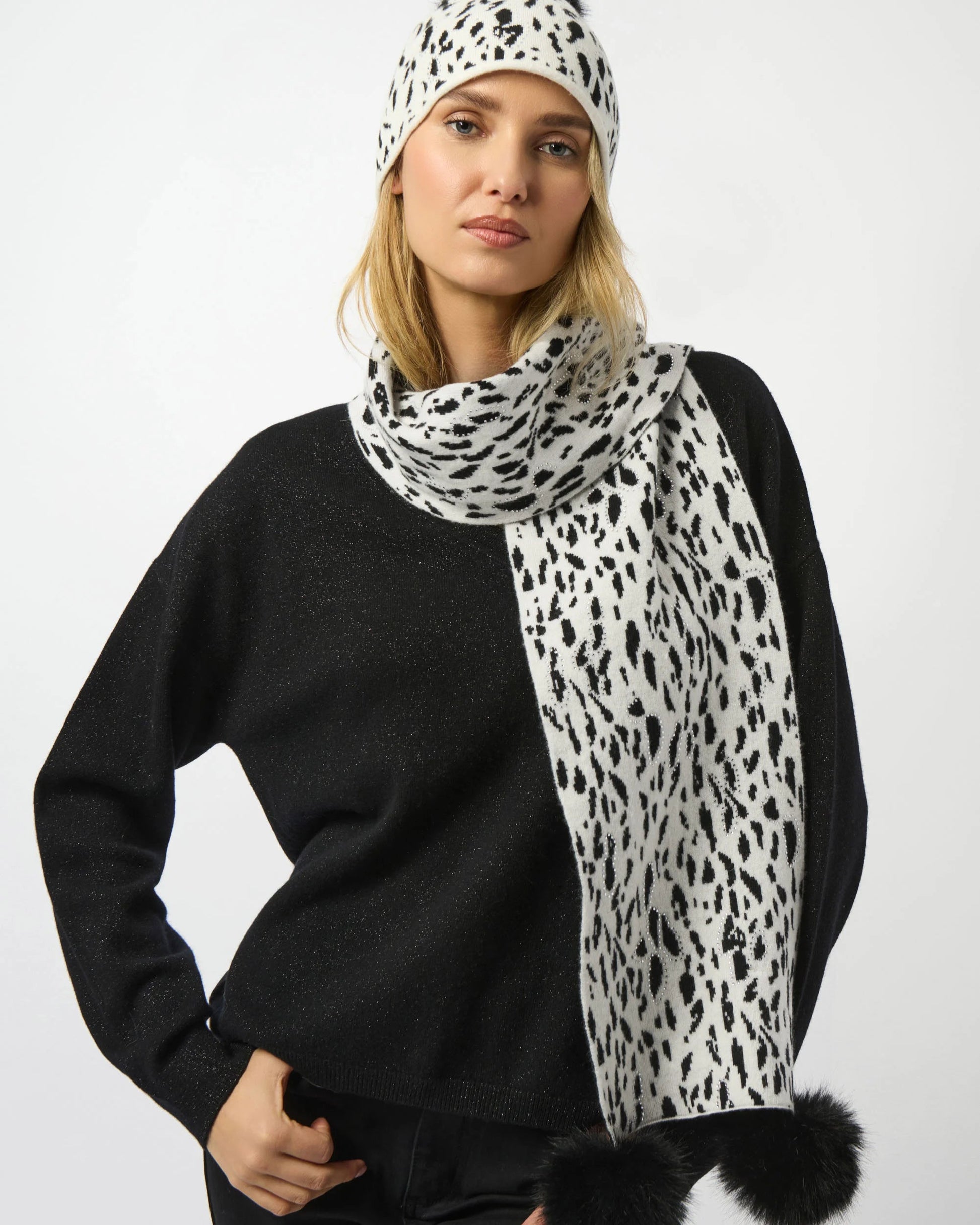 Woman wearing a black sweater and a white scarf with black leopard print pattern on a white background