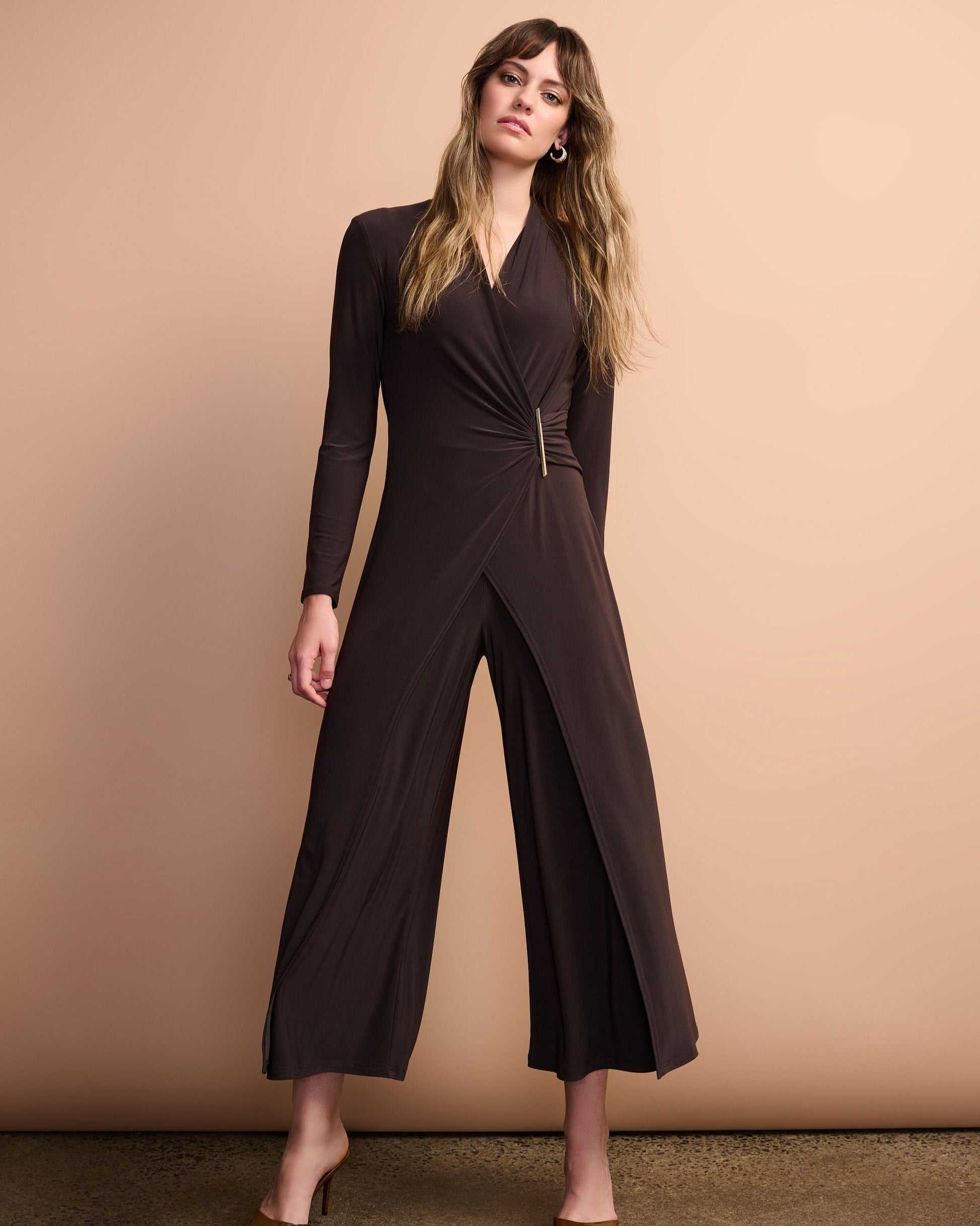 Woman wearing a brown jumpsuit against a beige background