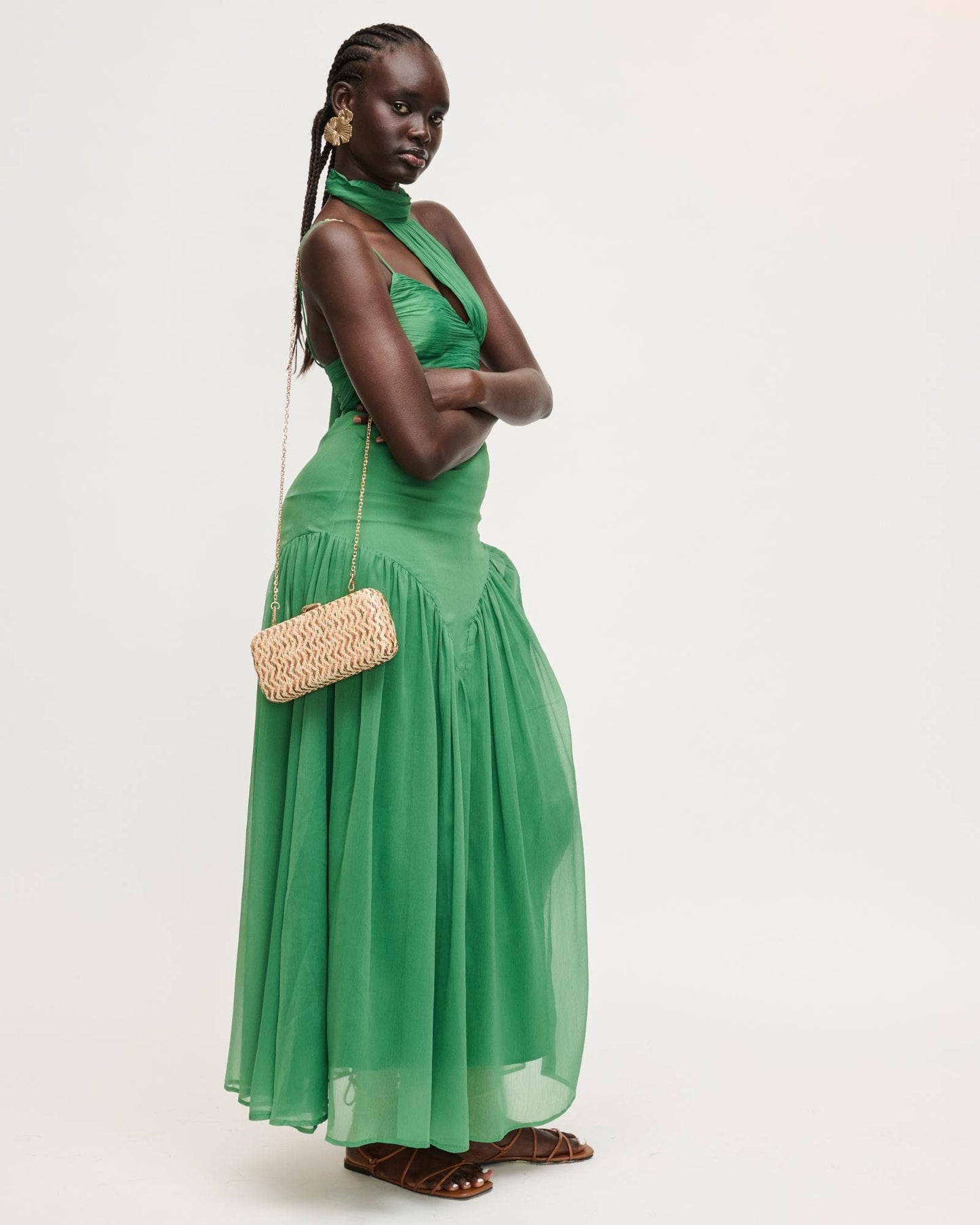 Woman in a green dress holding a straw bag on a white background