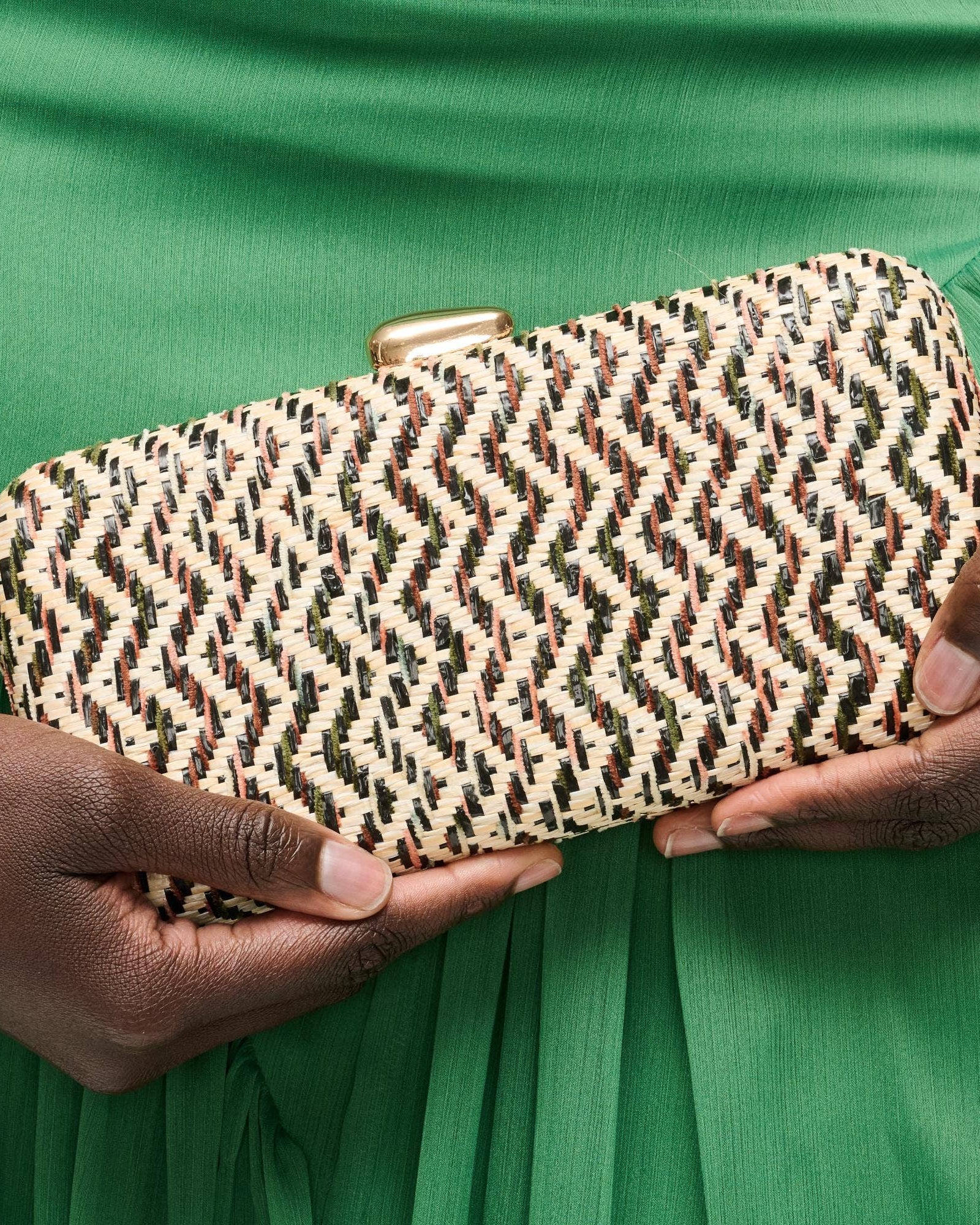 Person holding a patterned clutch against a green background