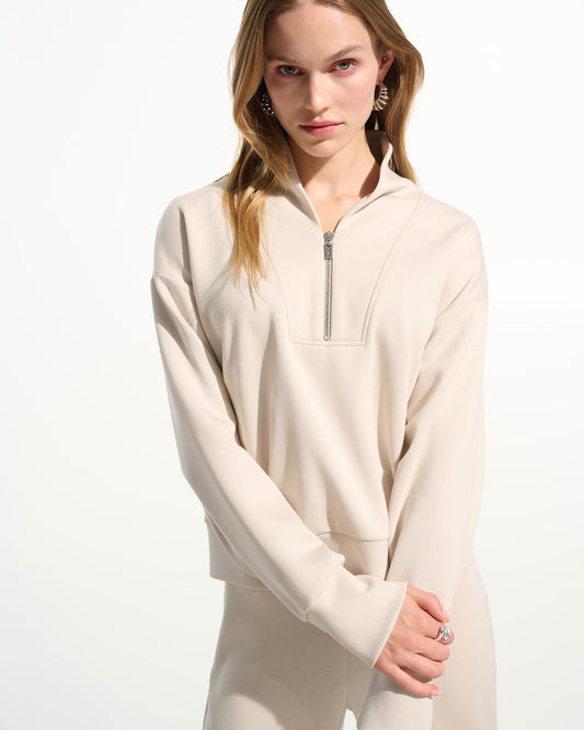 Woman wearing a beige half-zip sweatshirt on a white background