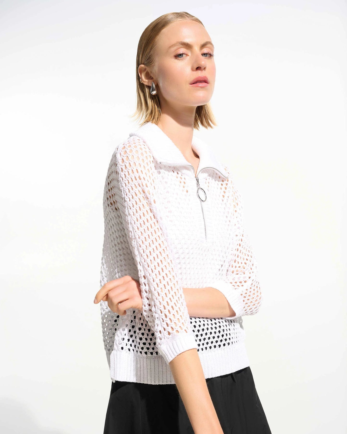 Woman wearing a white mesh top and black pants on a white background