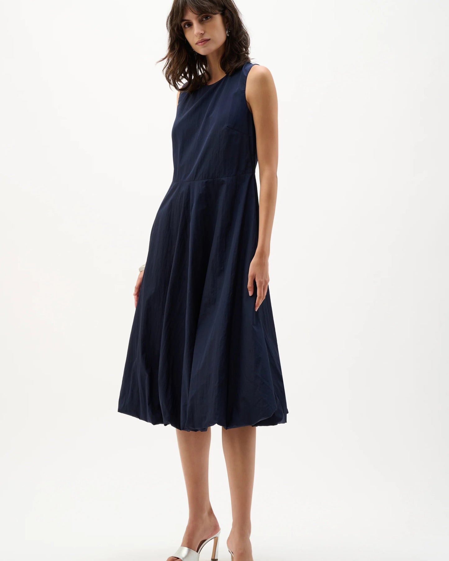 Woman wearing a navy sleeveless dress on a white background