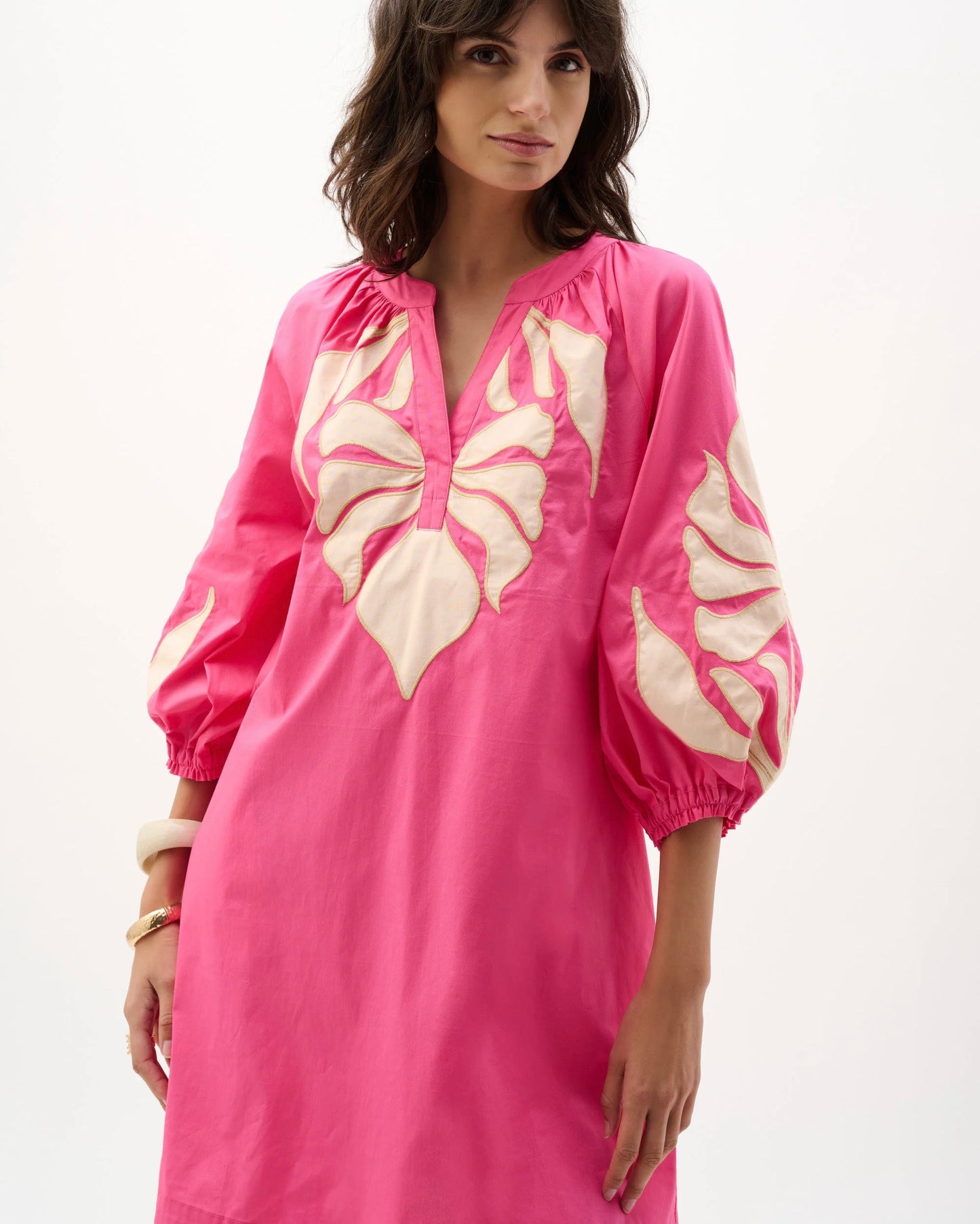 Woman wearing a pink dress with butterfly patterns on a white background