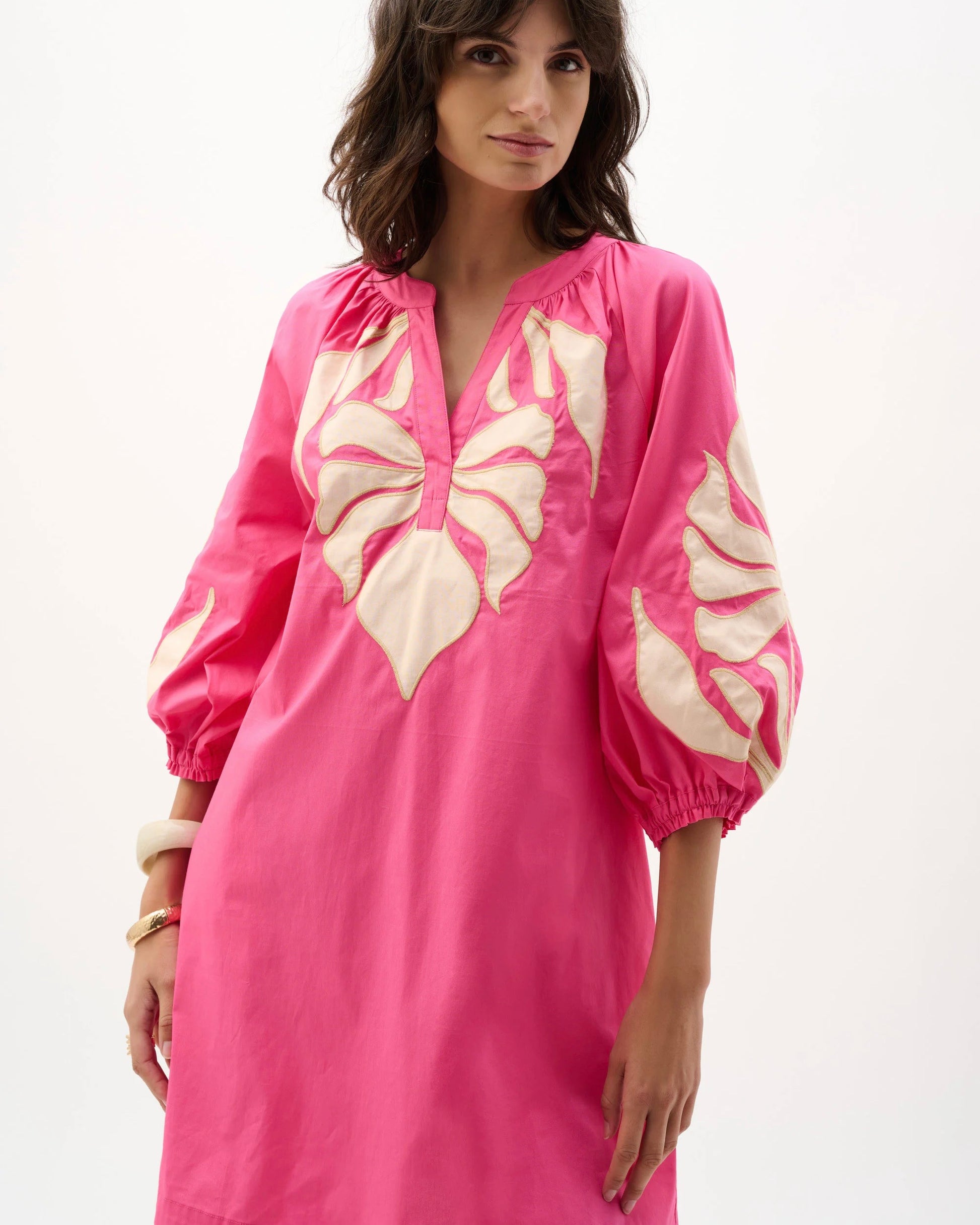 Woman wearing a pink dress with butterfly patterns on a white background
