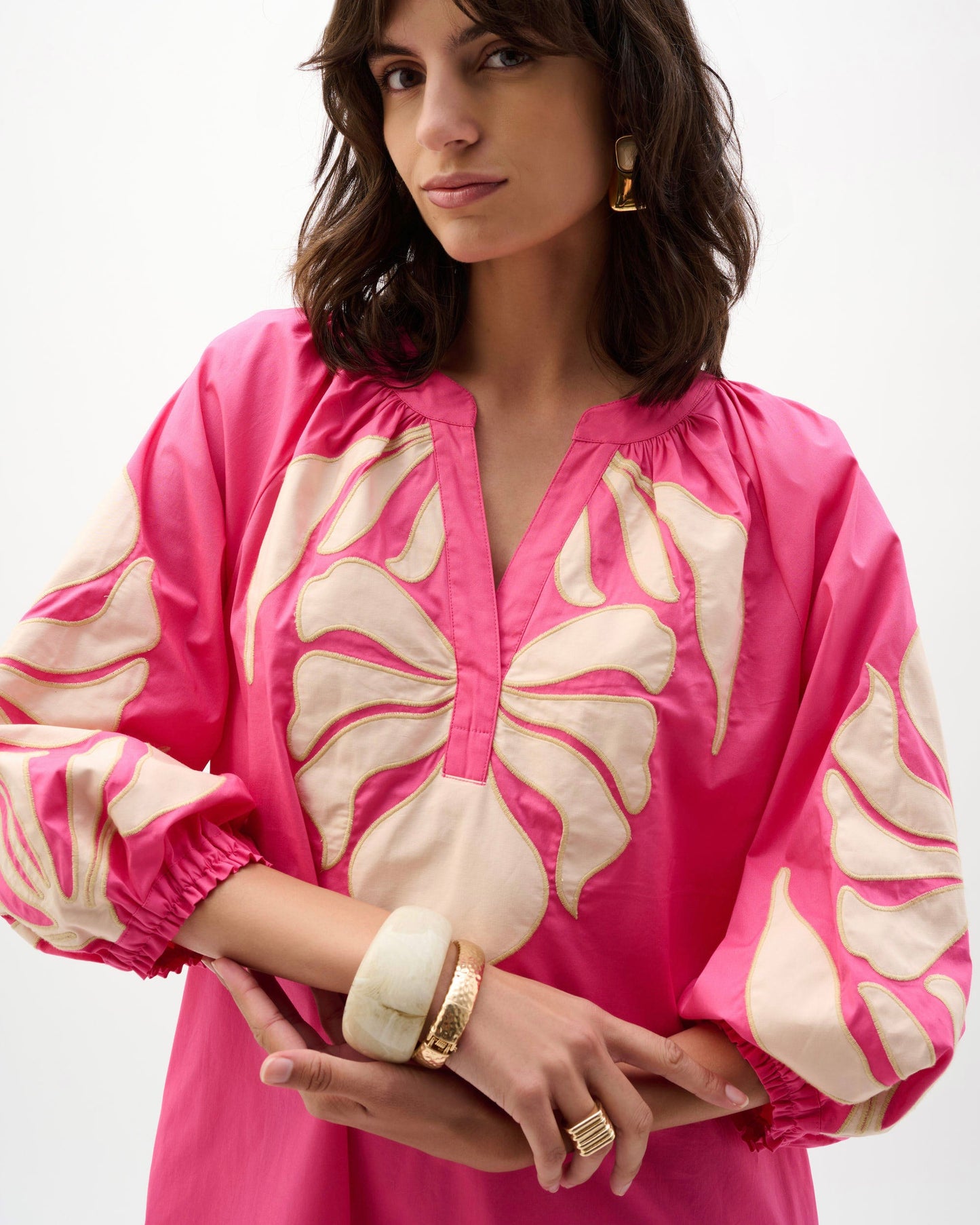 Woman wearing a pink blouse with floral patterns on a white background