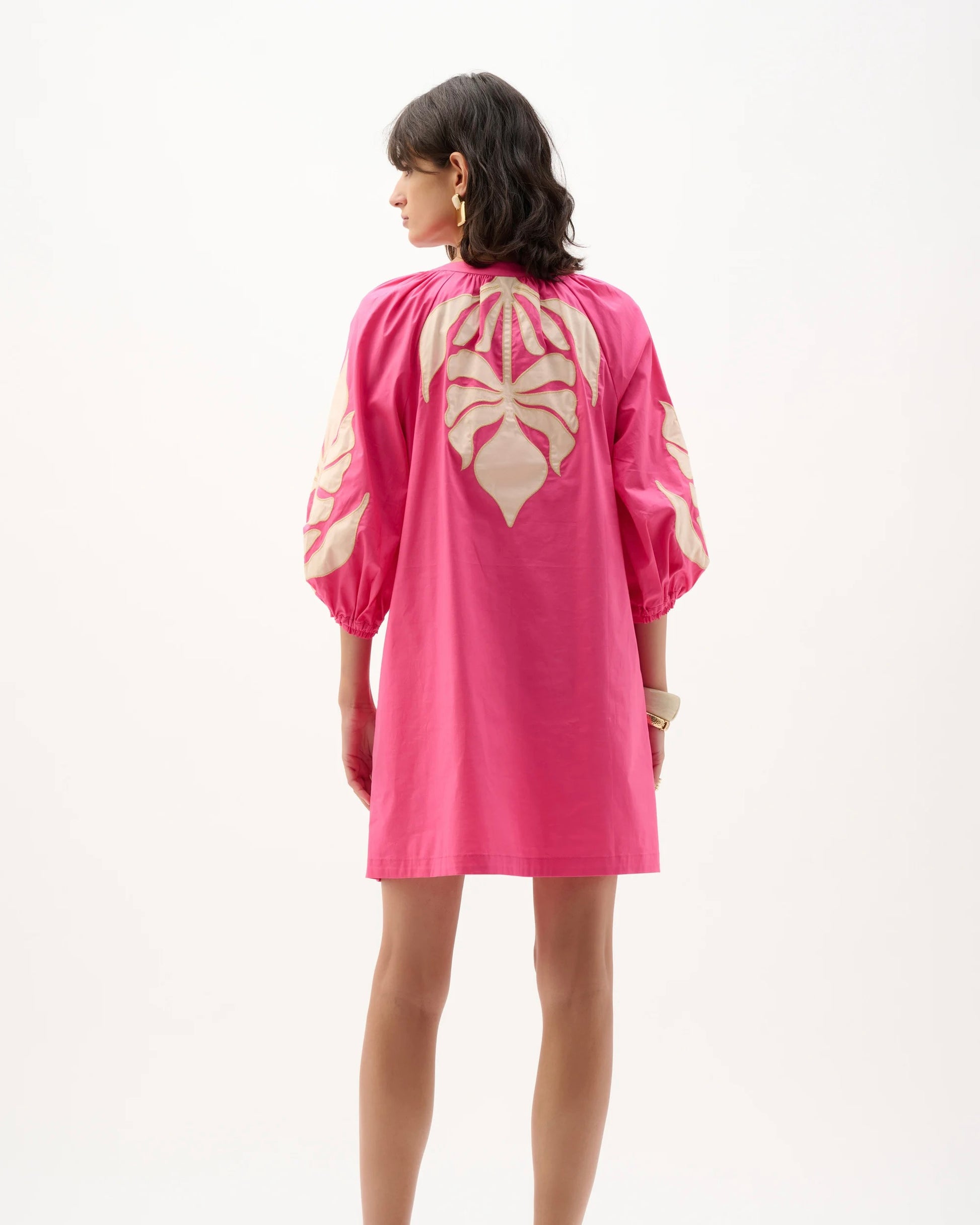 Woman wearing a pink dress with a heart pattern on a white background