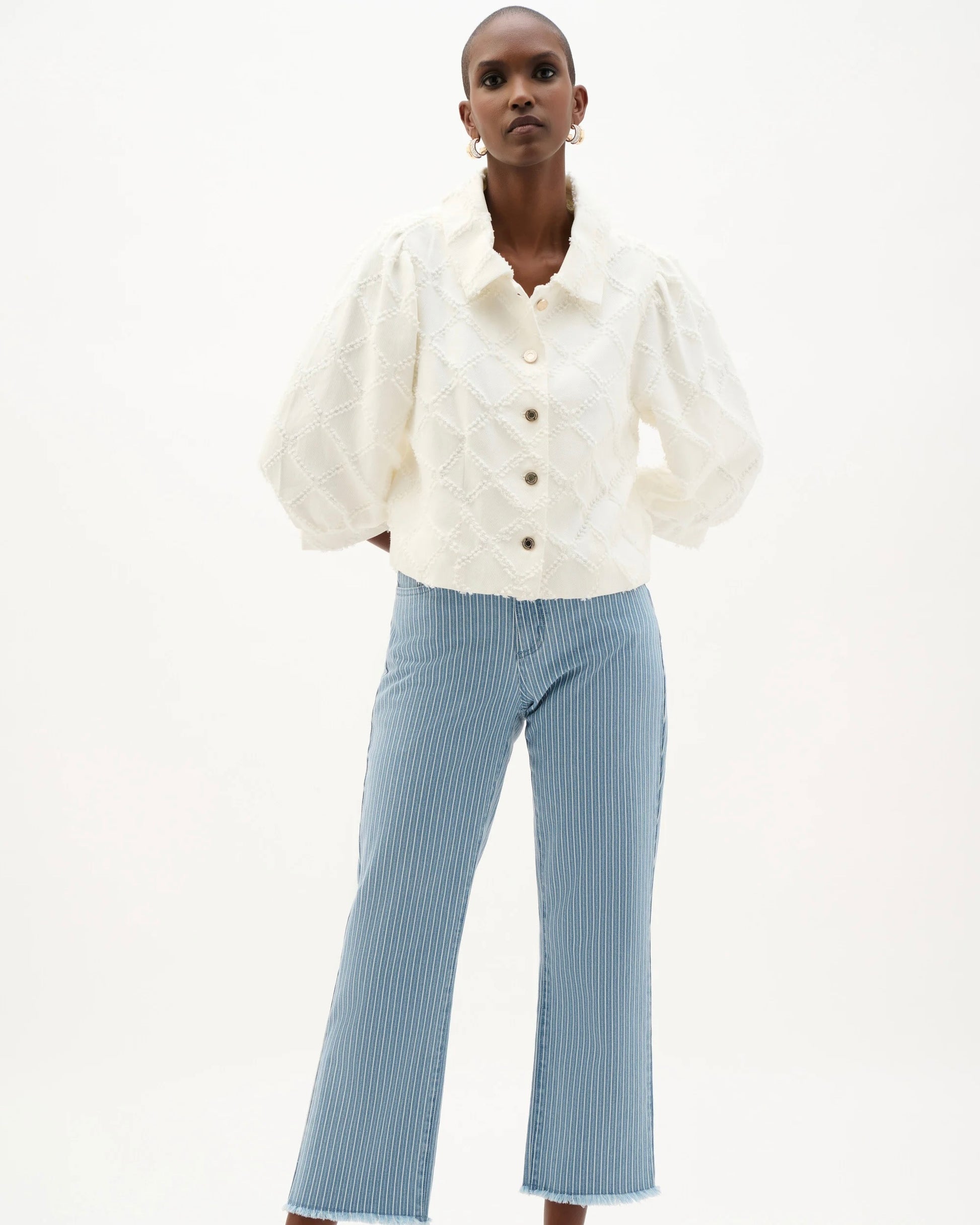 Person wearing a white blouse and light blue pants on a white background