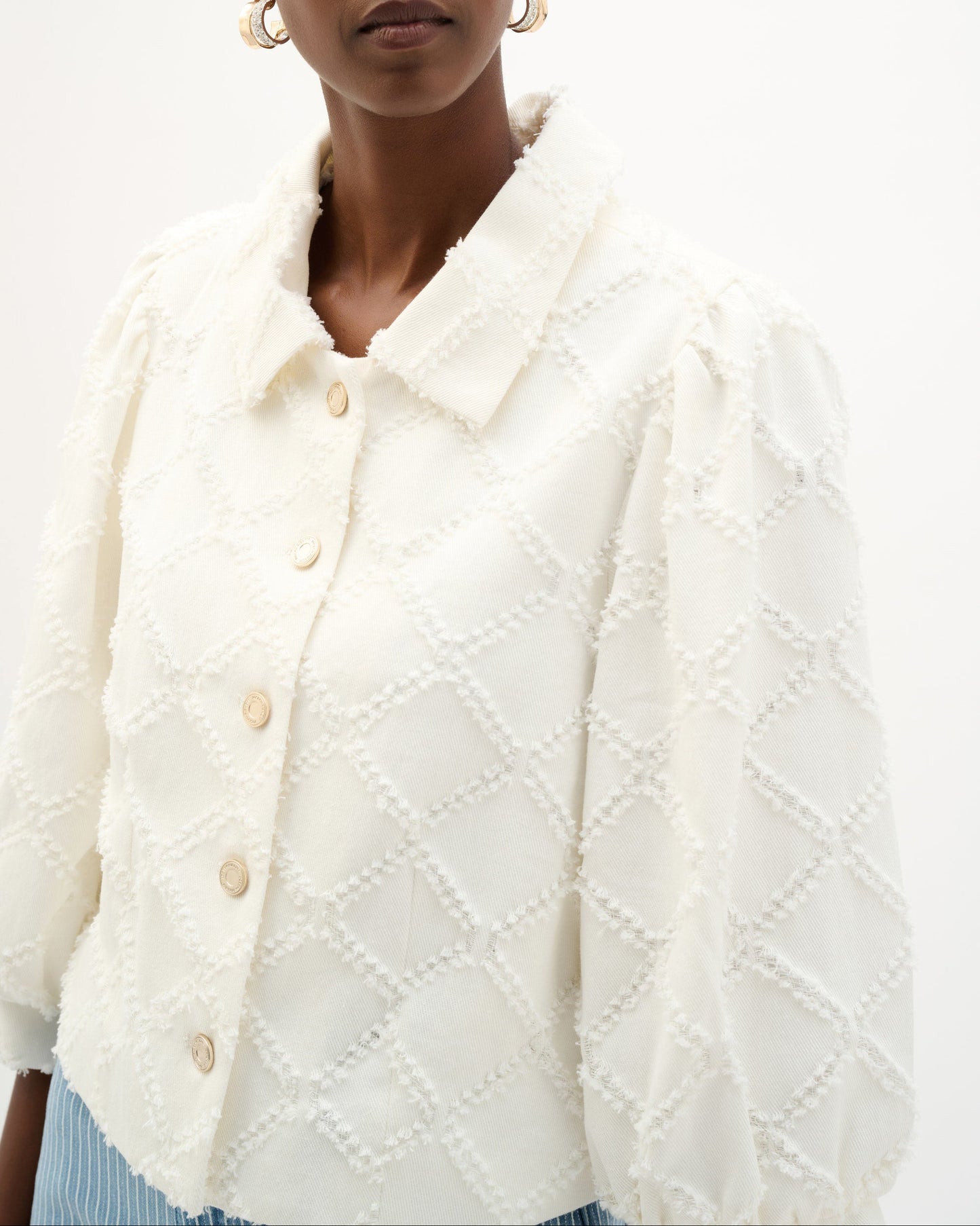 Woman wearing a textured white cardigan against a plain background