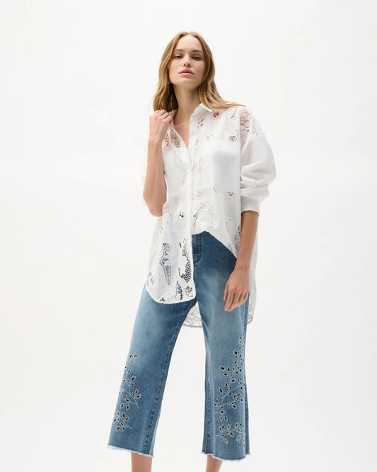 Woman wearing a white blouse with floral patterns and blue jeans on a white background