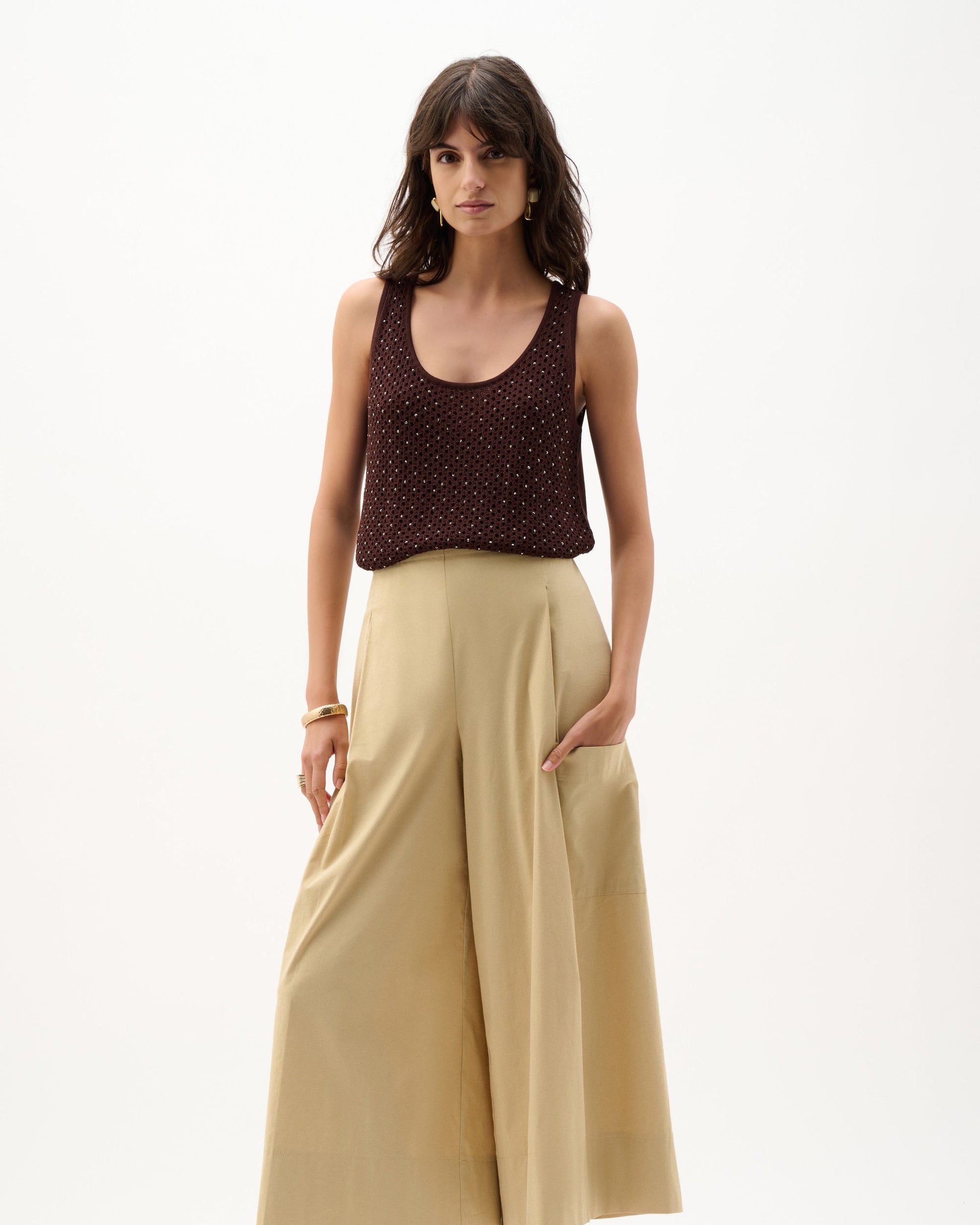 Woman wearing a brown top and beige wide-leg pants on a white background