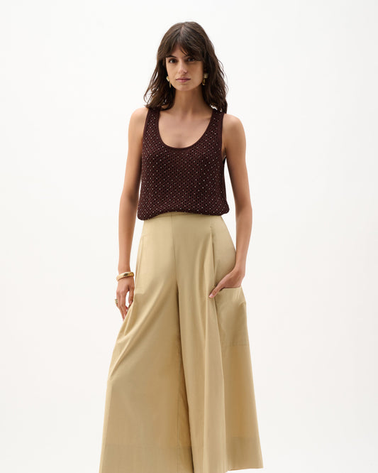 Woman wearing a brown top and beige wide-leg pants on a white background