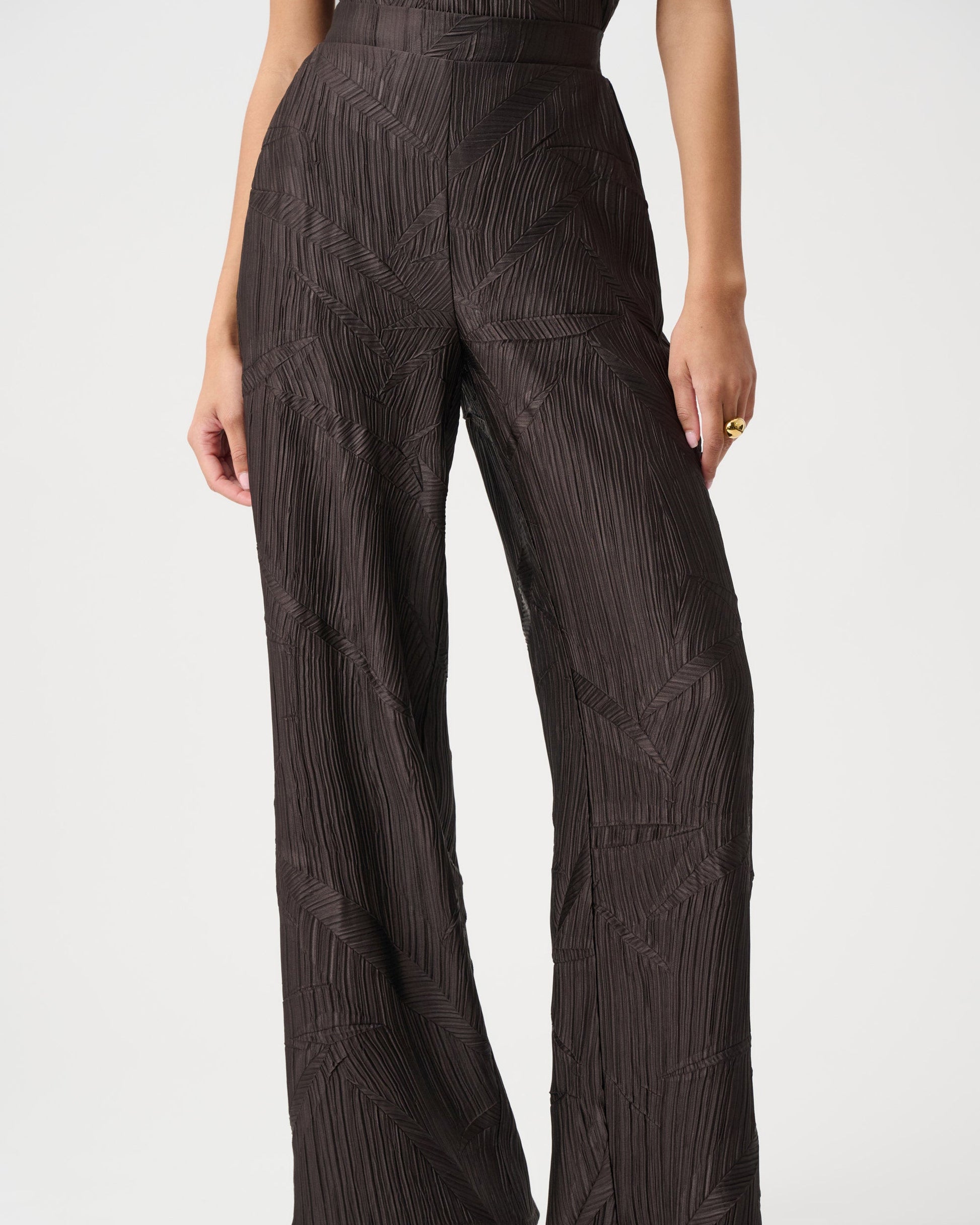Person wearing brown patterned pants on a white background