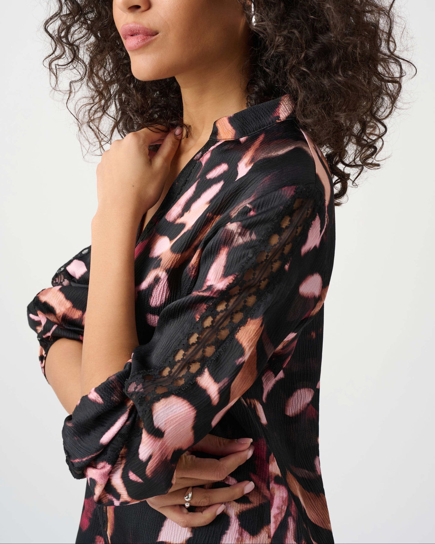 Woman wearing a black and pink patterned dress against a white background