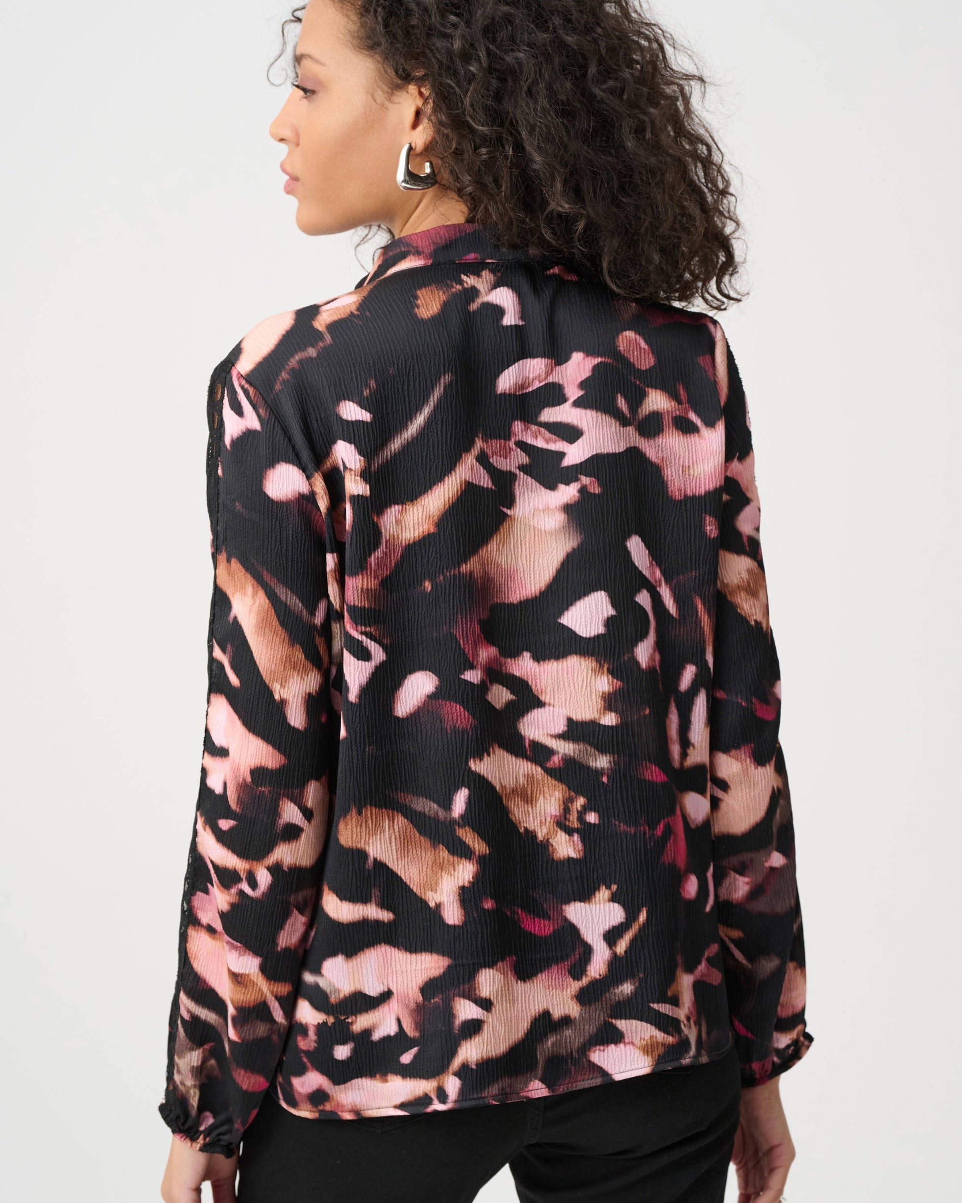 Woman wearing a patterned blouse with a neutral background
