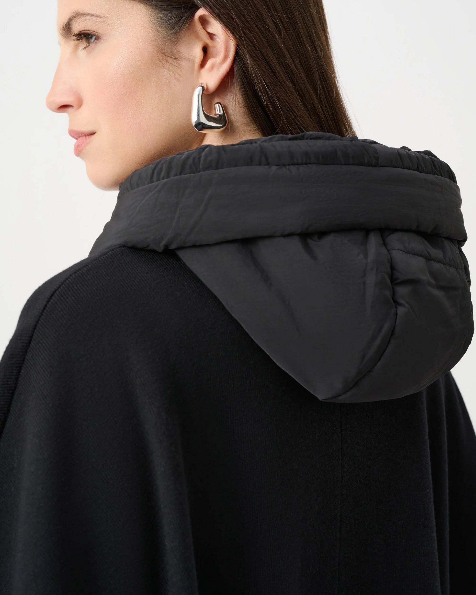 Person wearing a black coat with a hood on a white background