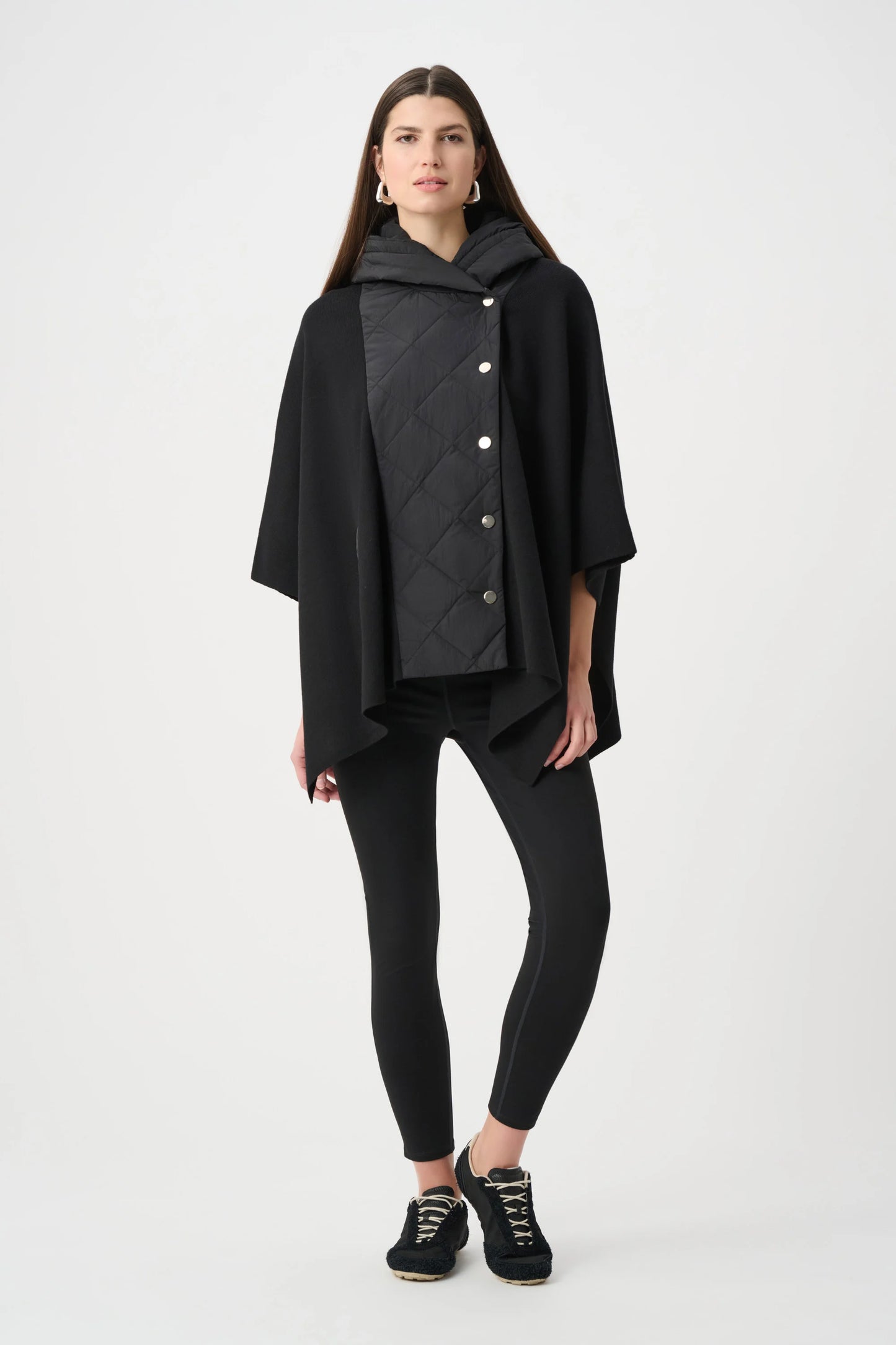 Woman wearing a black quilted poncho on a white background