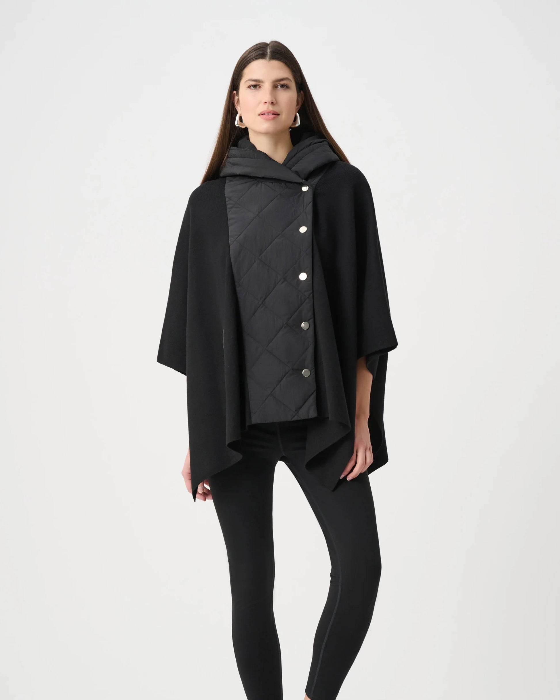 Woman wearing a black quilted poncho on a white background