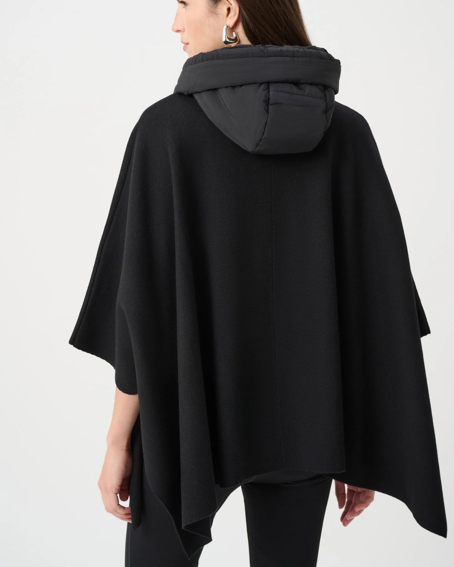 Woman wearing a black poncho with a hood on a white background