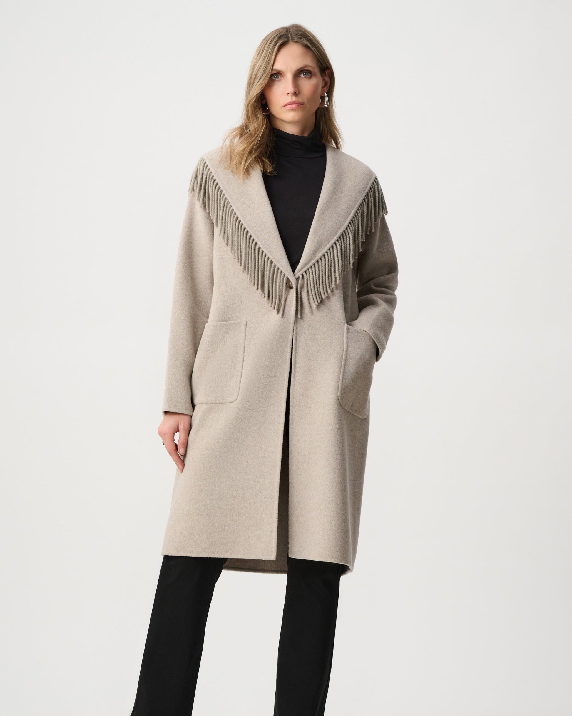 Woman wearing a beige coat with fringe details on a white background