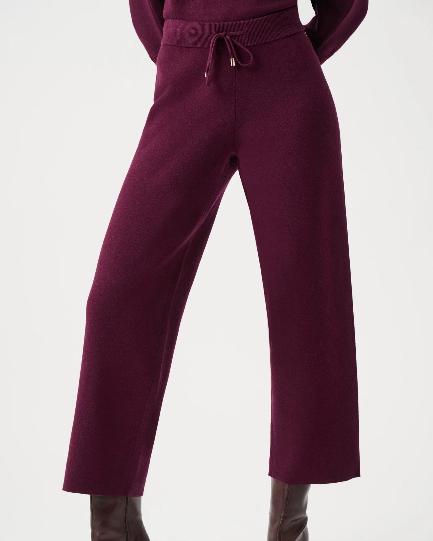 Purple outfit with high-waisted pants and brown boots on a white background