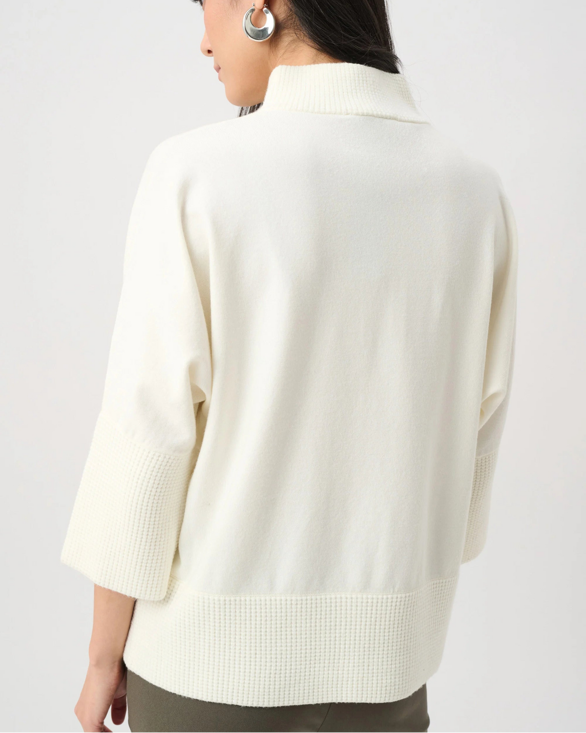 Person wearing a cream-colored sweater on a plain background