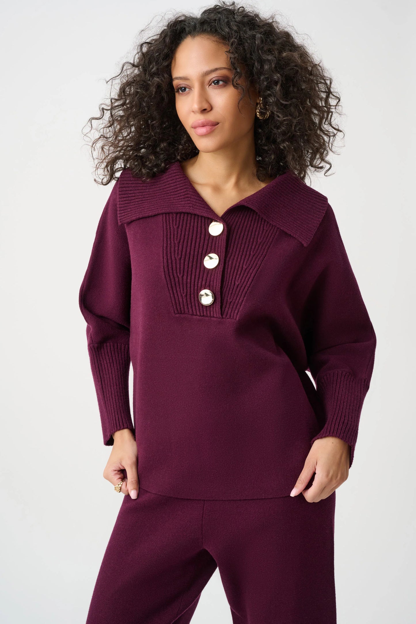 Woman wearing a burgundy outfit with a buttoned collar on a white background