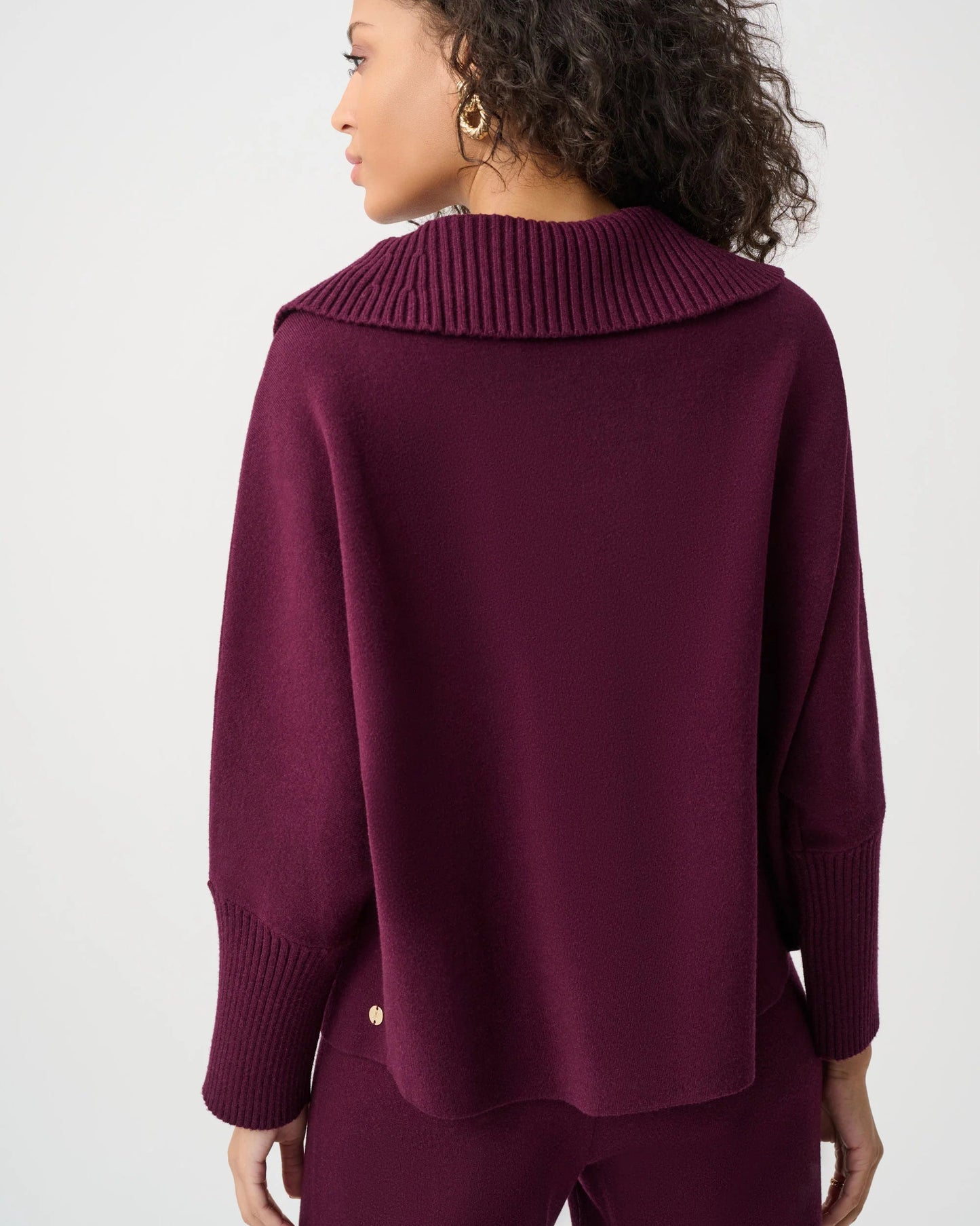 Person wearing a burgundy sweater and pants on a white background