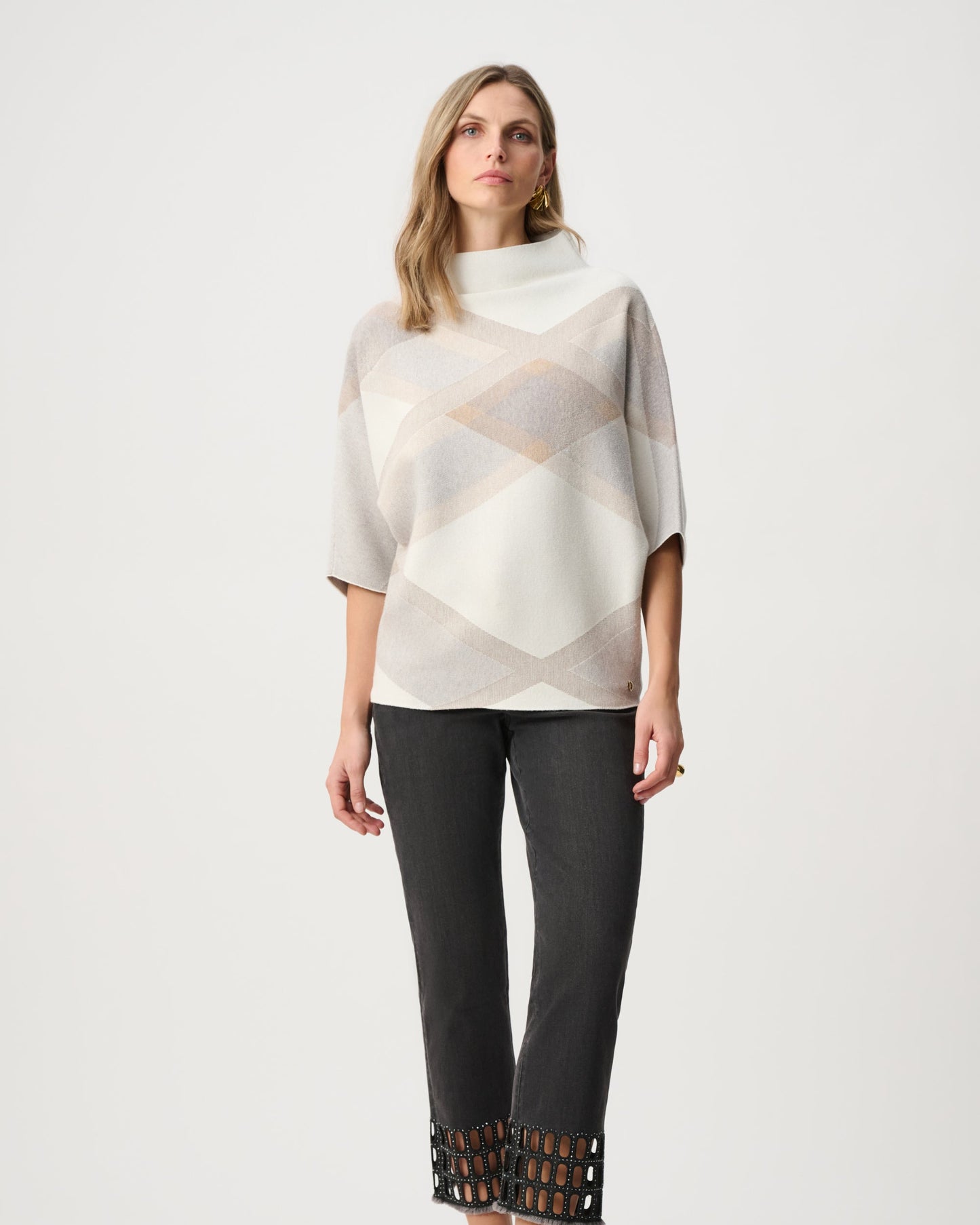Woman wearing a patterned top and black pants on a white background